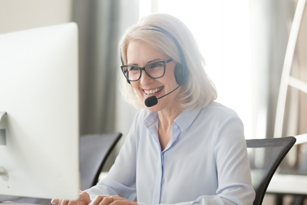 Happy,Old,Businesswoman,In,Headset,Speaking,By,Conference,Call,Looking